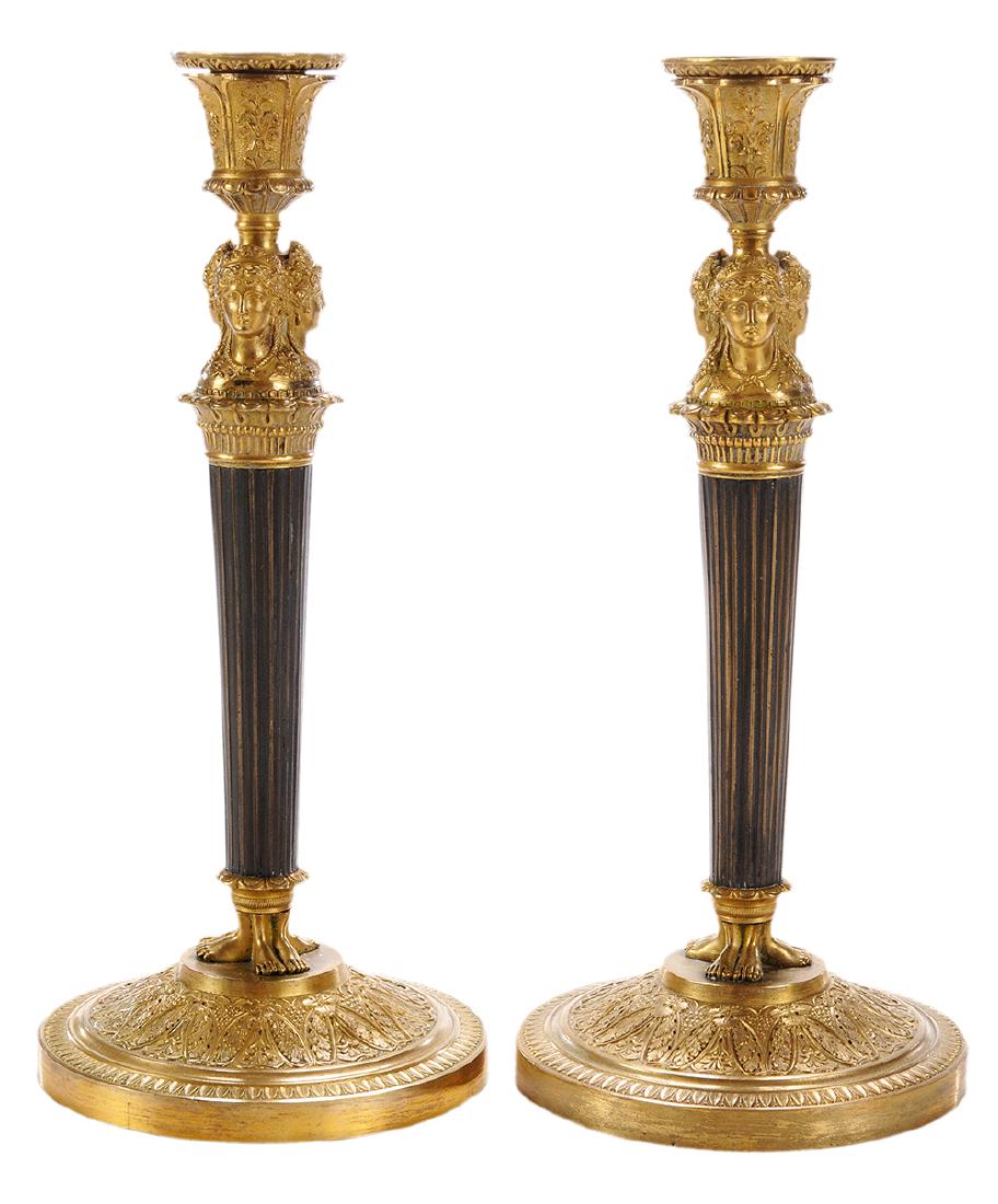 Pair French Empire Bronze Candlesticks: French, 19th century, removable wax nozzles capping the three maiden mask support raised on tapering reeded posts, domed circular machine turned bases, 11-3/4 in.. Provenance: Property from the Collec