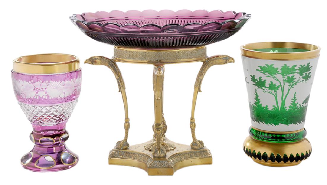 Continental Glass Compote and Two Drinking Glasses: 19th century, amethyst cut and hand polished glass tazza supported by a brass base comprised of four eagle head supports ending in ball and talons, resting on a stepped acanthus leaf base with a centr