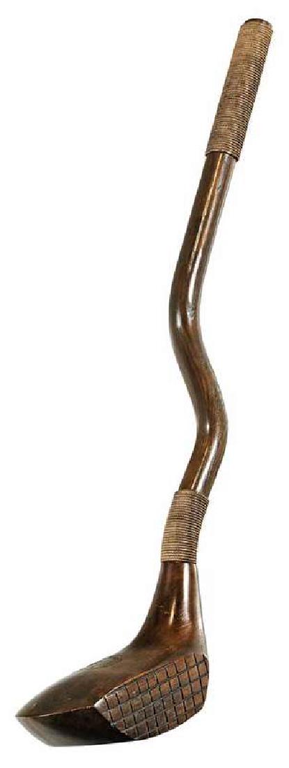 Oversized Carved Walnut Golf Club: circa 1970s, inscribed "Wee Birdie Driver", possibly made by Baker, in walnut and other woods, the handle wrapped in rope, 42 in.