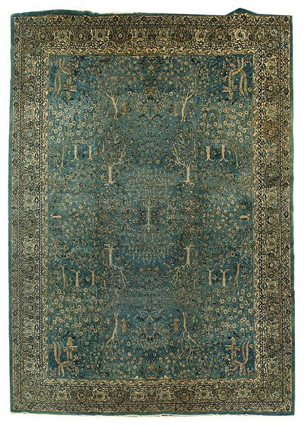 Finely woven Indo-Persian rug,: double book-matched design, elaborate garden designs with animals on blue central field, trees, winged birds or cats chasing birds in each corner, border with faces, 12 ft. x 17 ft. 3 in. Generally ev