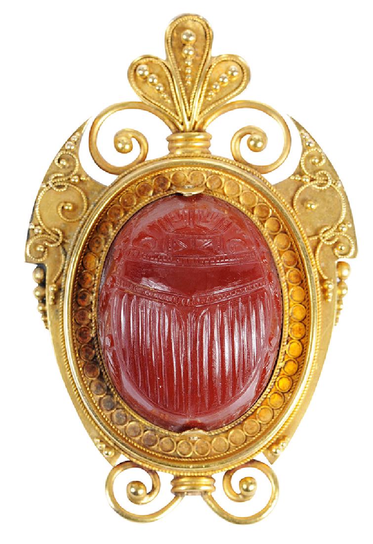 18kt. Scarab Brooch: Etruscan Revival, canetille details, center carved carnelian scarab bead, locket with glass on back, tested 18kt. yellow gold, 2 x 1-1/4 in., 20.7 grams