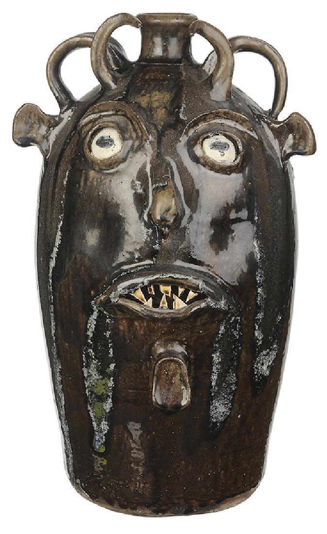 Large Wayne Hewell Devil Jug: (Lula, Georgia, late 20th/21st century) dark brown runny alkaline glaze, greenish gray and blue melt runs down face and back of jar, applied features including white clay eyes, broken china teeth, cur