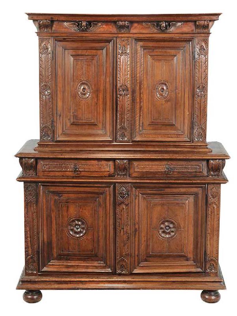 An Italian Baroque Carved Walnut Cupboard: Continental, 17th/18th century, leaf, rosette, and winged angel carved motifs, four doors and two dovetailed drawers, 70 x 51 x 23 in.