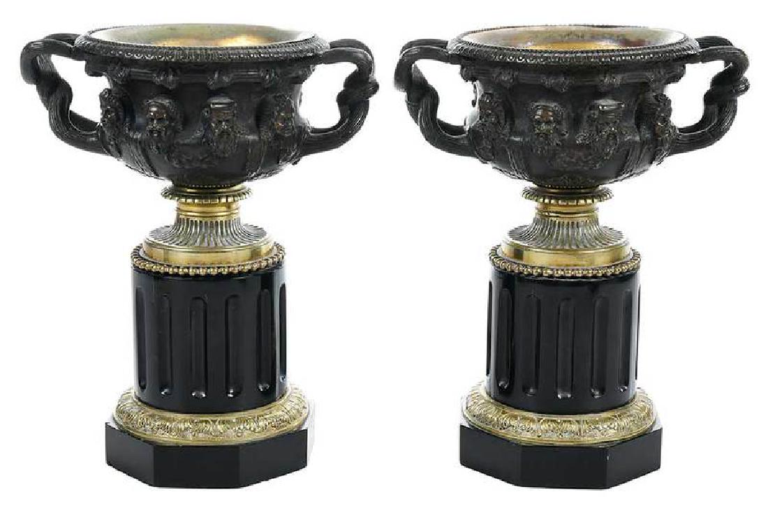Pair Grand Tour Bronze Warwick Vases: Continental, 19th century, patinated vases with twisted handles, decorated in relief with eight heads, on marble columnar form bases, with gold colored metal liners, 11 in.