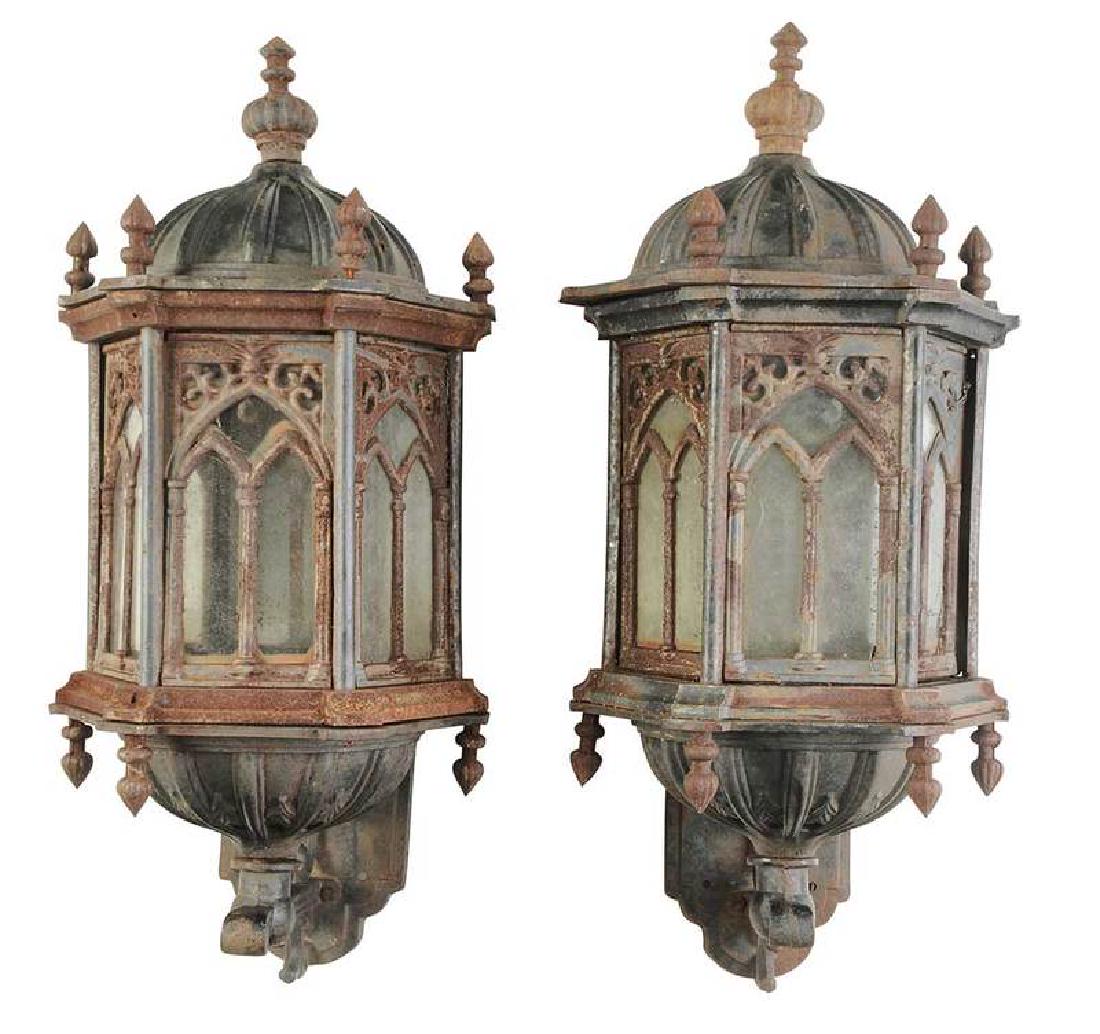 Pair of Gothic Revival Lanterns with Brackets: American, late 19th century, iron and glass, six sided form, arched glass panels with scrolling elements, domed top and base, tear drop finials, resting on iron wall brackets, 27 x 14 x 12 in.