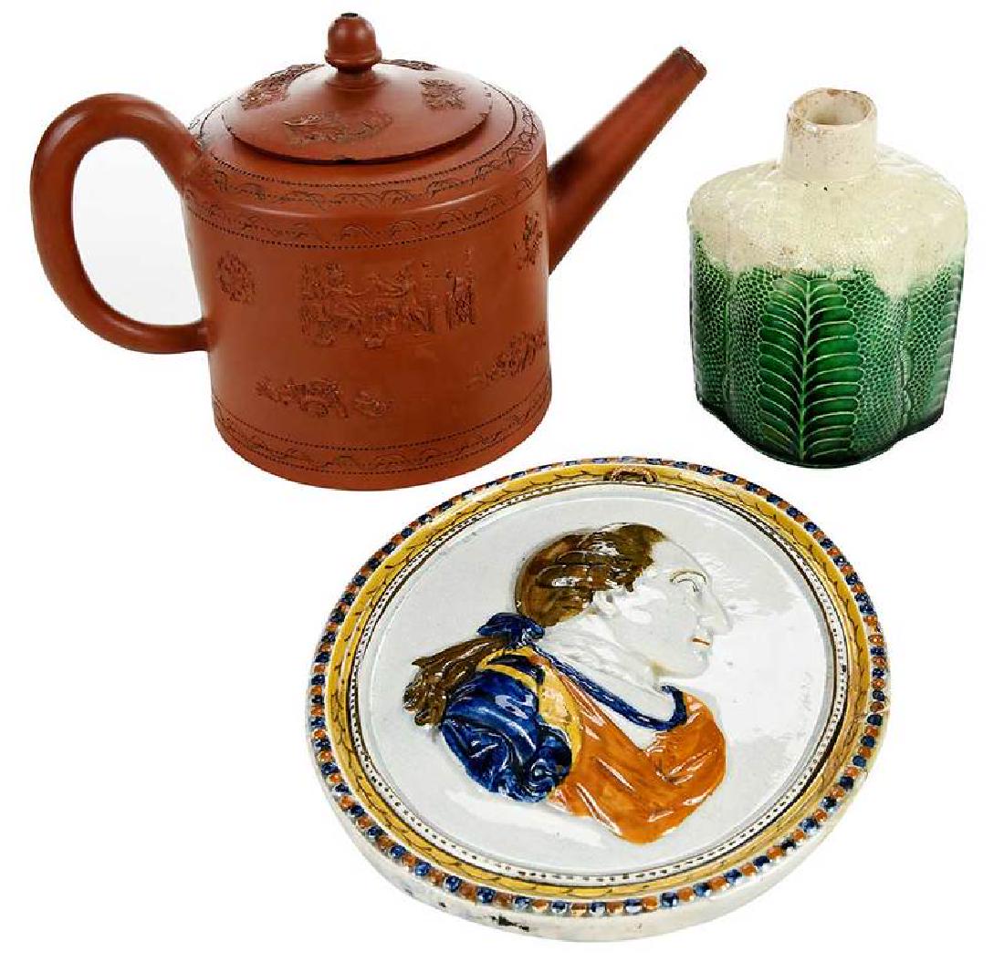 Three Pieces Early British Pottery: early 18th/19th century, redware teapot with applied sprigged decoration, possibly Elers Brothers factory, circa 1700, 5-1/2 in.; losses to relief decoration; cauliflower majolica bottle or caddy, 4 i