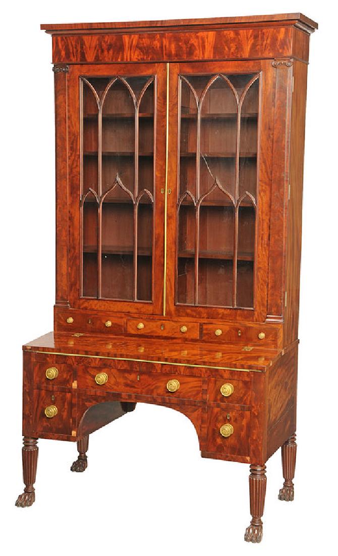 Fine Classical Figured Mahogany Bookcase: New York, circa 1825, possibly from the shop of Duncan Phyfe, highly figured veneers, original gilt brass lion mask pulls, carved paw feet on front and back, arched glazed doors, finely constructed, m