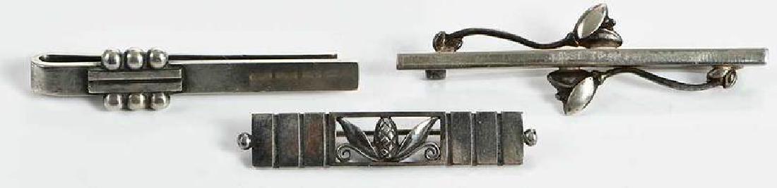 Three Pieces Georg Jensen Sterling Silver: tie bar, design 61, Harold Nielsen, 2 x 7/16 in., 9.4 grams [tarnish, scratches and wear]; brooch, design 216A, Johan Rohde, 5/16 x 1-7/8 in., 4.8 grams [tarnish, wear and scratches]; brooch, design 2