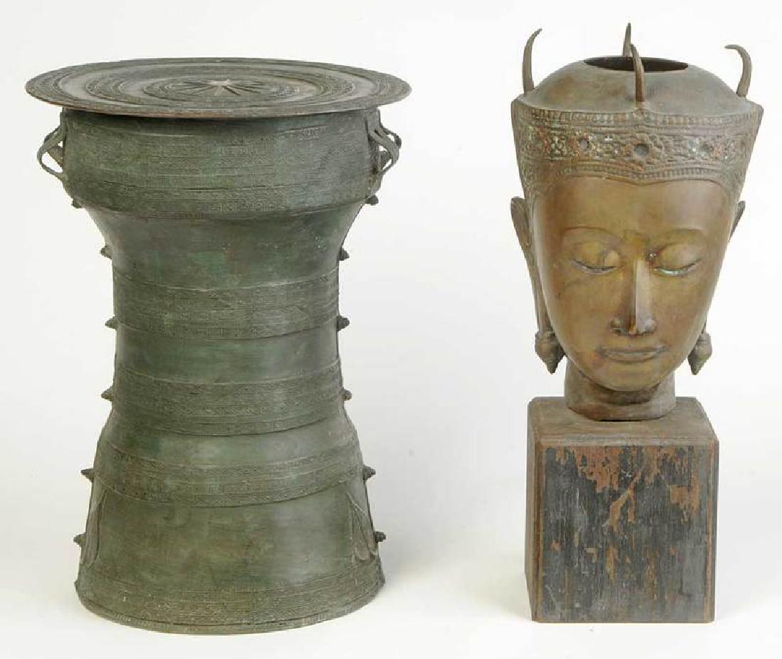 Southeast Asian Buddha Head, Rain Drum: 20th century, head set on a painted wood plinth, open at crown; drum with incised meander decoration, 20 in. Provenance: Private Collection