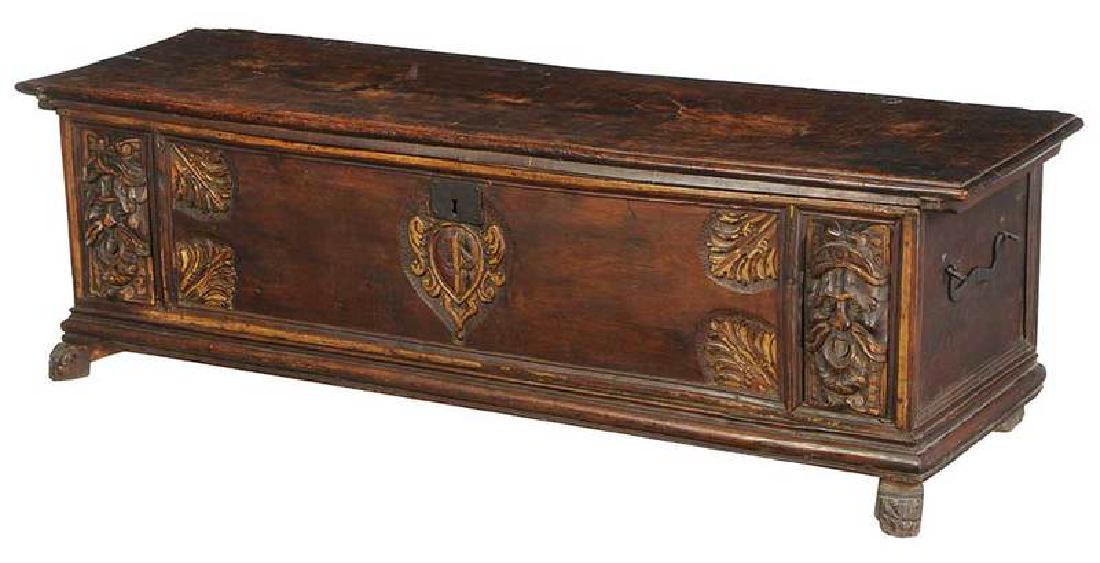 Italian Baroque Carved Walnut Cassone: 17th/18th century, heavy lid with original iron lock and strap hinges, mask and leaf carved front centering an armorial crest, gilt and paint traces, iron carrying handles, 20 x 67 x 21 in. Prove