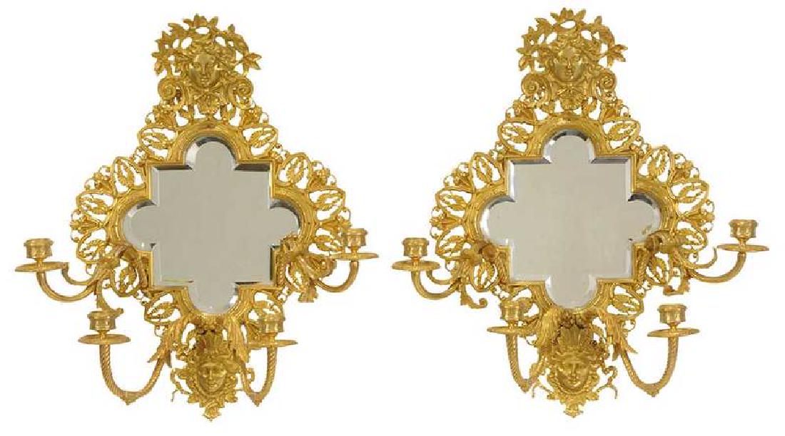 Pair Neoclassical Style Gilt Bronze Wall Sconces: Continental, 20th century, quatrefoil shaped beveled mirror plates over four leafy and twisted candle arms, female faces and open foliate decoration, 20-1/2 in. Provenance: Property From an Important 