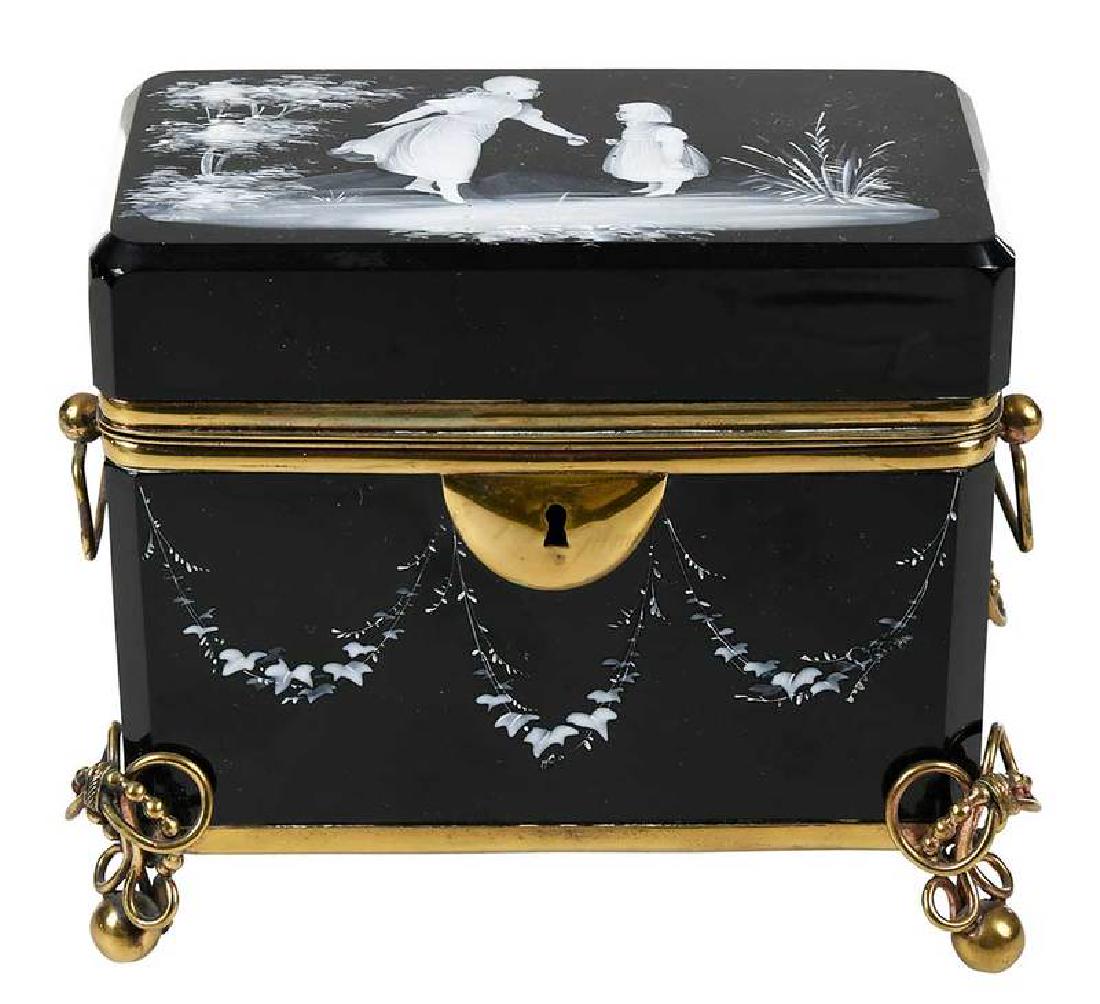 Mary Gregory Style Black Glass Casket Box: late 19th century, black Bohemian glass with Mary Gregory style white enameled scene of two children on lid and ivy vine swags on sides, fits in gilt brass stand with bale handles and lock, 5 x 5-1/2 