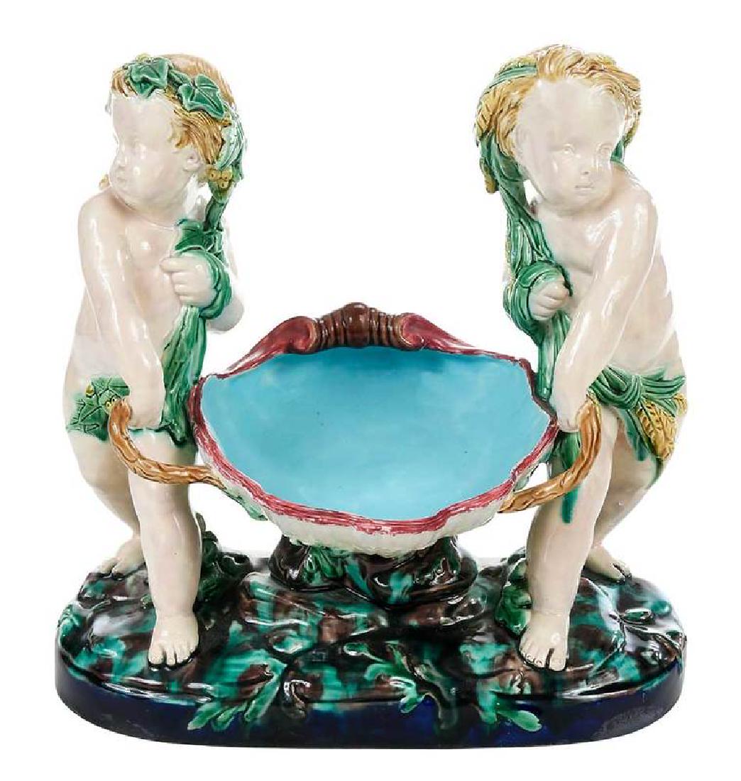 Mintons Majolica Centerpiece: British, mid-19th century, depiction of two putti carrying a clam shell, impressed "Mintons" on base, 11 x 11 in.