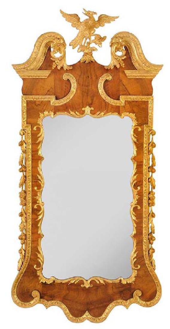 George II Walnut and Parcel Gilt Mirror: British, mid 18th century, finely figured bookmatched walnut veneers, scrolled pediment with leaf and berry streamers, centering a well carved phoenix finial, 51 x 25 in. , Provenance: Sales Label for