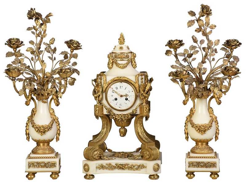 Louis XVI Style White Marble Clock Garniture: French, mid to late 19th century, three piece gilt bronze and white marble garniture, sides set with jasper ware panels of classical figures, gilt floral, lyre, bow, and wreath embellishments, flame f