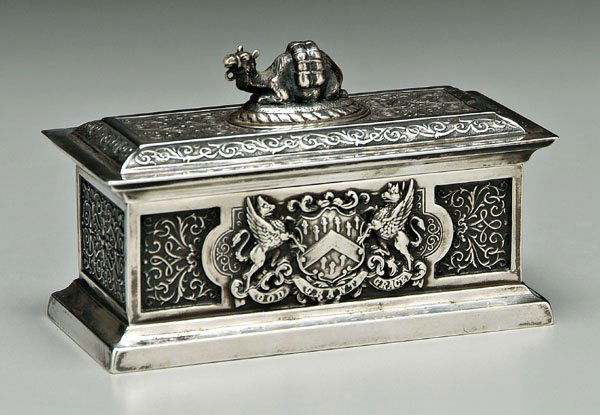 English silver box,: rectangular with camel finial, [possibly lacking chain], scroll decoration, sides with winged lions, shield and ribbon "GOD GRANT GRACE", marks for John Marshall Spink, London, 1897, .925 fine, 5.48 o