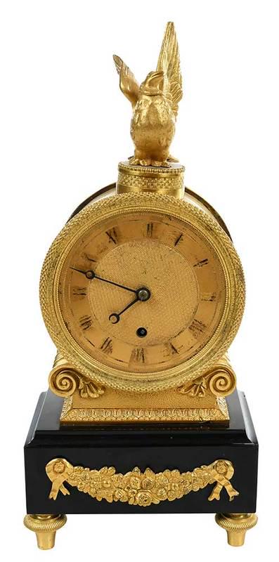 French Empire Gilt Bronze and Marble Clock: early to mid 19th century, rectangular black marble base with gilt bronze mounting of floral swag, surmounted by a circular gilt bronze case enclosing gilt clock dial with Roman numerals, bird form fi