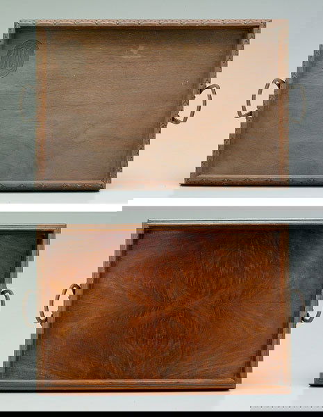 Two Tryon Toymakers trays: one with bookmatched walnut veneers, hand-hammered handles, marked "Tryon Toymakers Wood and Woodcarvers, Tryon, NC", 2-1/2 x 23 x 14-1/2 in.; one walnut with oval cartouche with carved "M", carved ge