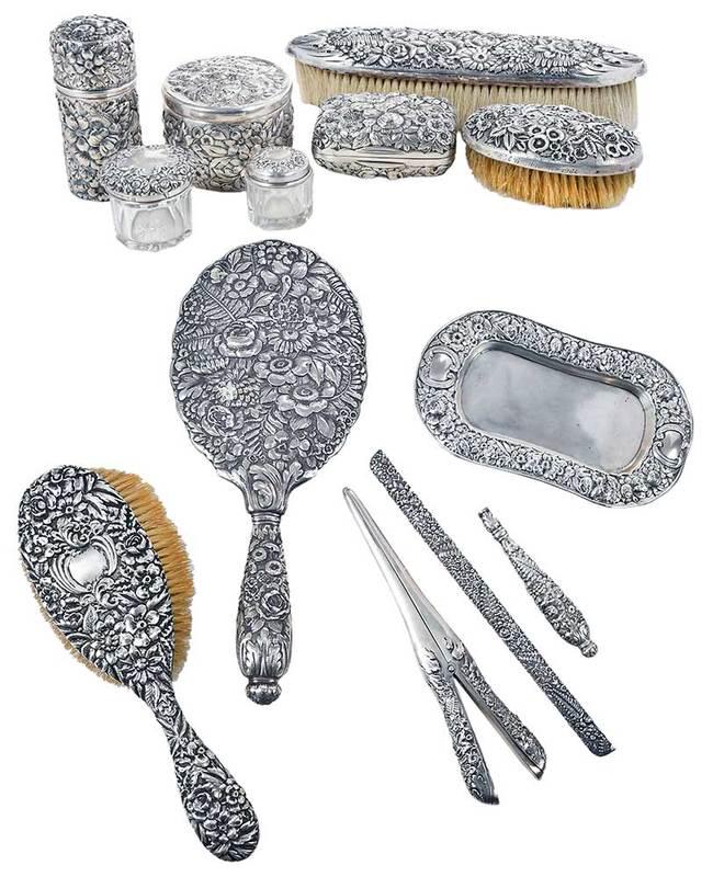 13 Repousse Sterling Dresser Pieces: American, 19th/20th century, all with repousse decoration, including Tiffany & Co hand mirror, brush, glove stretcher, comb and handle; Gorham pin tray, two glass jars with sterling lids, soap box; Wh