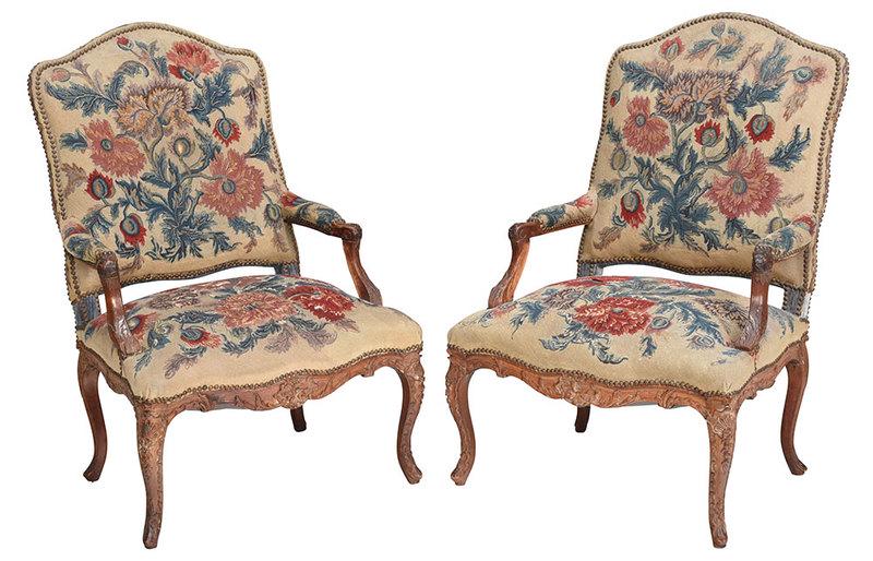 Pair of Provincial Louis XV Walnut Arm Chairs: French, 18th century, each with leaf and shell carved frame set with early needlework upholstery with brass tacking and blue velvet backs, 41-1/2 in.Provenance: Private Florida Collection