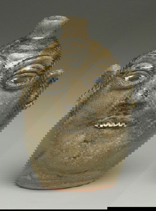 Stoneware face jug, mottled and runny me: Stoneware face jug, mottled and runny medium olive alkaline glaze, bulging painted eyes, applied ceramic teeth, base marked "Lanier Meaders," firing cracks in nose and eye area, 9-1/2"