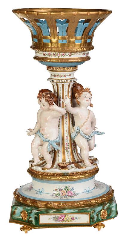Tiche Louis XV Style Porcelain Centerpiece: Italian, 20th century, reticulated basket supported on a fluted column flanked by four putti,ÿraised on a faux malachite painted octagonal base, decorated throughout with floral cluster transfers and