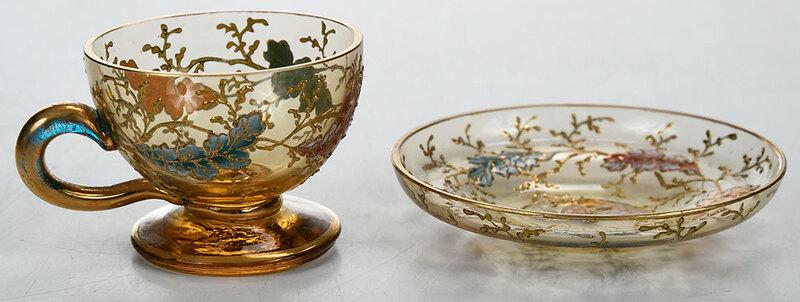 Moser Enamel Decorated Footed Cup and Saucer: Continental, late 19th century, gilt and enamel decorated honey colored glass with scrolling oak leaves, footed cup, 1-1/2 in.; saucer with early label "Ludwig Moser", 3 in. diameterÿ, Provenance: De