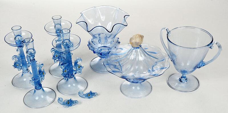 Seven Pale Blue Venetian Glass Table Items: Italian, 20th century, four candlesticks, each with a fluted shaft flanked by three dolphins, 8-1/2 in.; urn form bowl with handles and stem base, 7-1/2 in.; flared rim bowl with stem base, 8 in.; sha