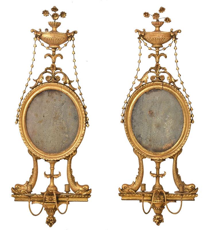Very Fine Pair Adam Carved Gilt Mirrored Sconces: British, late 18th century, with urn tops over bellflower chains, centering oval mirror plates, resting on dolphin figural supports over double candle arms, 39 x 14 in.; Provenance: Max Weber Antiques