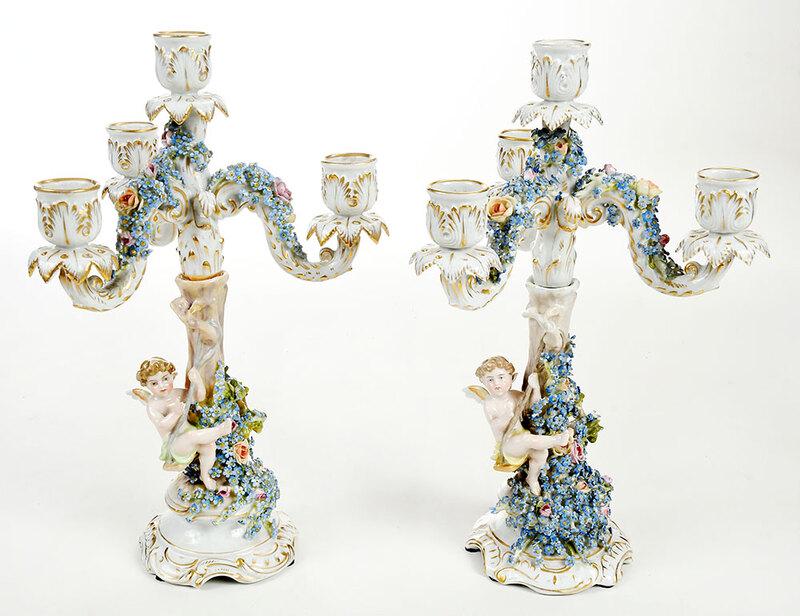 Pair of Schierholz German Figural Candelabra: early 20th century, each with cherub hanging from a tree branch and supporting a central shaft with three foliate candle arms, underglaze mark of crown over shield with three oak leaves on base, 13-1/