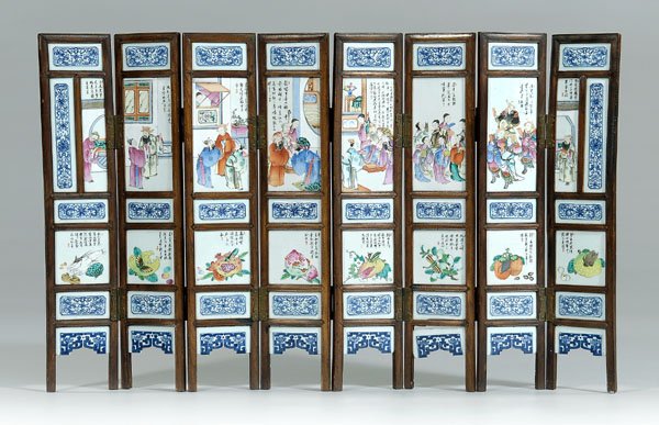 Chinese diminutive eight-panel screen,: hardwood frame with shaped bronze hinges, each panel inset with blue and white porcelain plaques of scrolling lotus and Buddhist symbols dividing polychrome plaques of court officials, ladies, soldier
