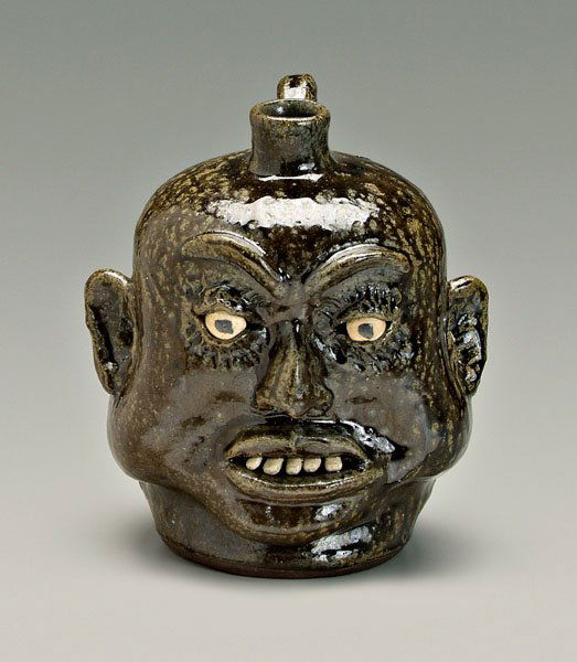 Lanier Meaders face jug,: runny alkaline glaze stoneware, heavy cheeks, inlaid ceramic teeth, articulated eyebrows, signed on base "Lanier Meaders" (White County, Georgia, 1917-1998), 10 in. Excellent condition. Provenance: Th