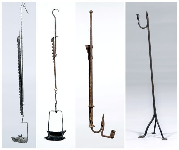 Four early iron lighting devices:: adjustable hanging rush lamp, spring adjusting device, 24 in. (closed), [extensive pitting;] tripod lighting stand with penny feet, candle socket and rush holder, 35 in., [legs bent;] hanging oil lamp