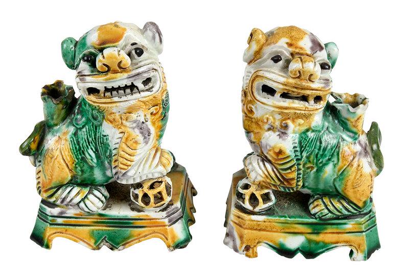 Pair of Chinese Sancai Glazed Foo Dogs: Qing, possibly Kangxi period, each with a defined face and open grimace showing teeth and tongues, an upright paw resting on a reticulated ball, and small cup protruding from back for joss sticks or i