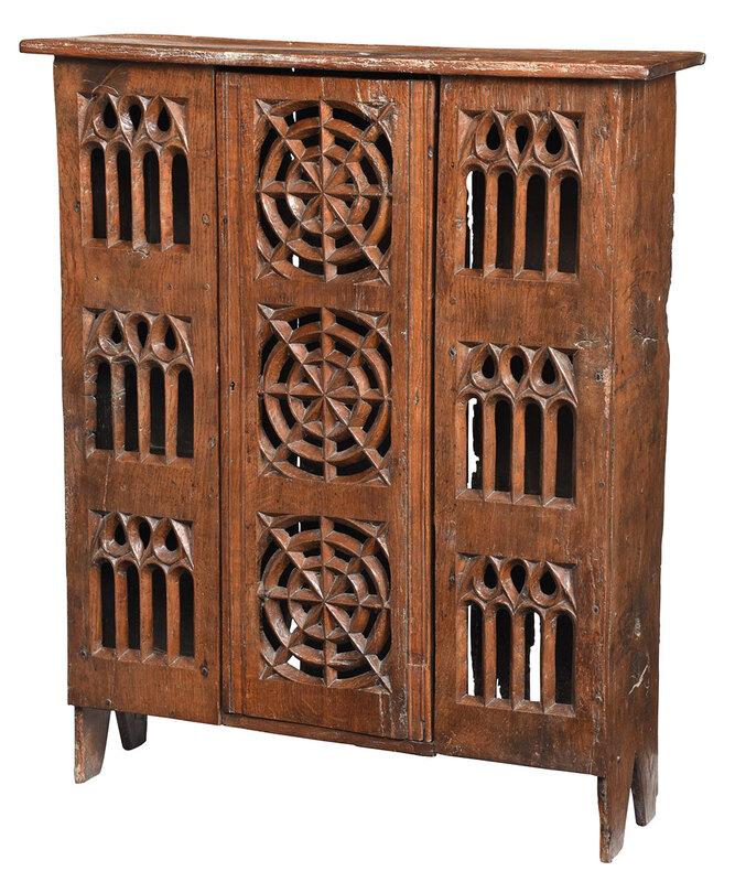 Very Rare Gothic or Tudor Carved Oak Cupboard: British or Continental, probably 16th century, cupboard or aumbry, oak throughout, central door with three pierced and carved sunburst motifs, early iron lock, flanked by three tiers of pierced Gothic