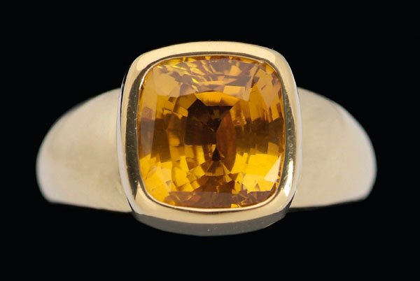 Golden sapphire solitaire ring,: square faceted cushion sapphire, estimated weight 5.56 oz.T., 18 kt. yellow gold mount, marks for Jewels That Dance (Asheville, North Carolina), size 5-1/2; insurance replacement value $6,458, with ap