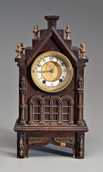 Gothic Revival shelf clock,: oak cathedral form, brass mounts, porcelain face, with key and pendulum, finial off but present, 18 x 8 x 5-1/4 in. Lacking top of back cover, veneer chips, cracks and losses, face loose and with mino