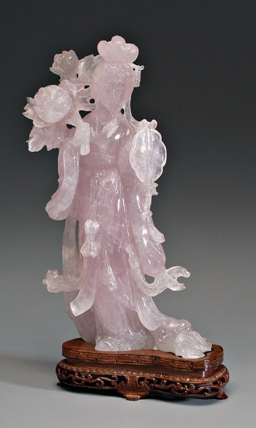 Chinese carved rose quartz figure,: elegantly coiffed beauty with flowing robes, fluttering ribbons, fan in her left hand, peony spray in her right hand, 20th century, 10-1/2 in., 12 in. on conforming wood stand. Natural inclusions, los