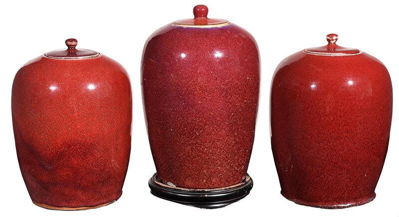 Three Chinese Sang de Boeuf Lidded Jars: Qing dynasty, lidded ovoid porcelain forms glazed in oxblood red, one with red wax seal to base, 12 in.; together with a stand - Provenance: Private Collection