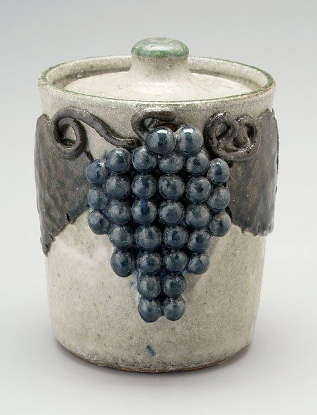 Lanier Meaders lidded canister: (White County, Georgia; Arie, Macon County, North Carolina, 1897-1989), cylindrical with applied grapes and leaves, blue and olive over white ground, base incised in script "Lanier Meaders", possibly