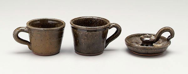 Three pieces Lanier Meaders pottery: (1917-1998, White County, Georgia), alkaline glazed stoneware, two tapered mugs, each 3-1/4 in.; candlestick, early 1970s, 3-1/8 in., [glaze creases as made, wax residue,] all with incised "Lanier Mea