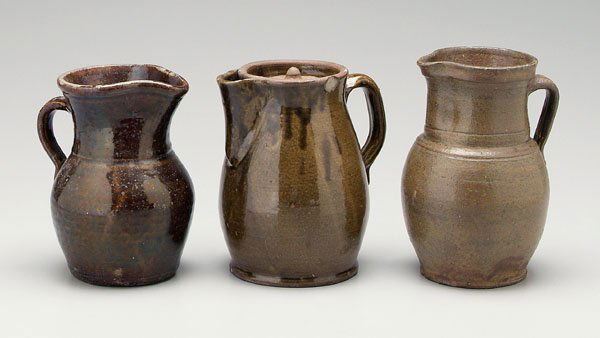Three alkaline glaze pitchers: one with tapered neck and bulbous base, speckled medium olive glaze, 8-3/4 in., Provenance: Billy Allen, 1977, [scattered rim chips;] one with lid, glossy medium olive glaze, found near Auburn, Alabam