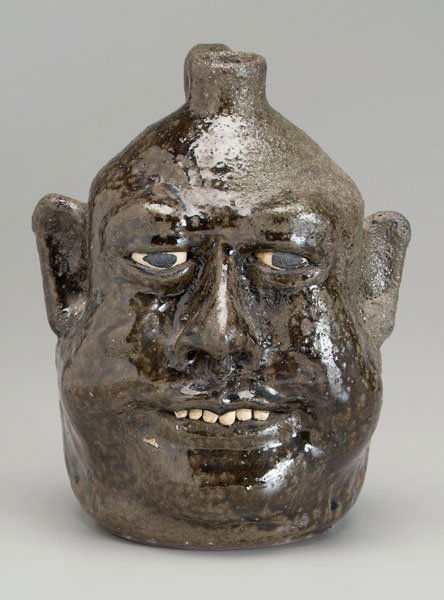 Lanier Meaders stoneware face jug: (White County, Georgia, 1917-1998), mottled olive alkaline glaze, ceramic teeth, base marked "Lanier Meaders 12-31-80", 9-1/2 in. Excellent condition, one side probably underfired. Provenance: Private