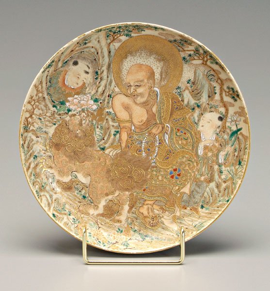 Satsuma plate,: seated lohan with two [karako] (Chinese children), Buddhist lion holding peony in mouth in a rocky setting, verso with scrolling lotus, base with gold two-character mark within oval, possibly Meizan, 