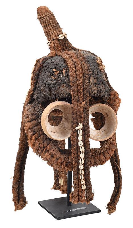 West African Dogon Fiber Mask: attributed to Mali, conical fiber head cover with protruding knop embellished with braids and cowry shells over eyes cut from split gourds, traces of pigment throughout, approximately 21 in.; with met