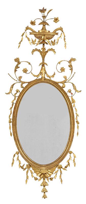 Fine Adam Carved Giltwood Oval Mirror: British, late 18th century, elaborate leaf and scroll crest centering urn issuing eagle's heads holding leaf and rosette streamer, oval plate with carved and gilt surround, 57 x 23-1/2 in. - Provenanc