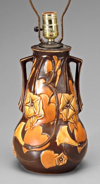 Roseville Morning Glory lamp,: yellow and orange flowers on brown ground on raised heart design, unmarked, probably Roseville made as lamp, 10-5/8 in. Four rim chips, chip to one handle and stem, other surface abrasions and losses.