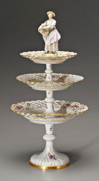 Meissen three-tier server: female figure at top with basket of flowers, each tier with reticulated border and hand-painted floral bouquets with gilt highlights, blue crossed swords mark under glaze, 21-1/4 in. Tiers in good con