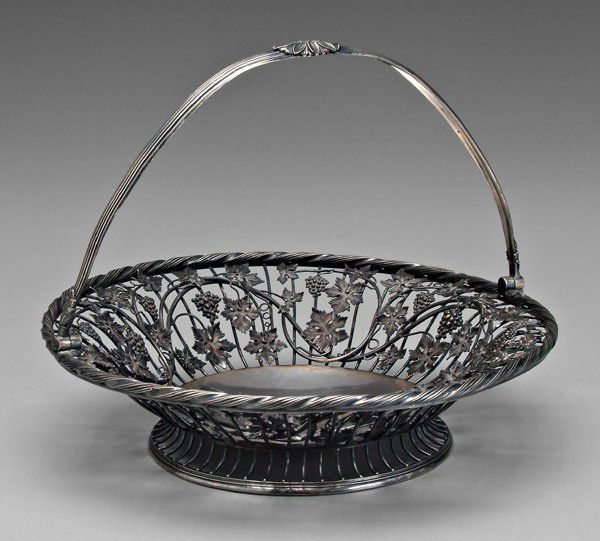 George III English silver basket,: round wirework sides with grape and vine decoration, solid floor with heraldic device, marks for Benjamin and James Smith, London, 1810, .925 fine, 53.84 oz.T., 10 x 13 x 12-3/4 in. Handle bent, light
