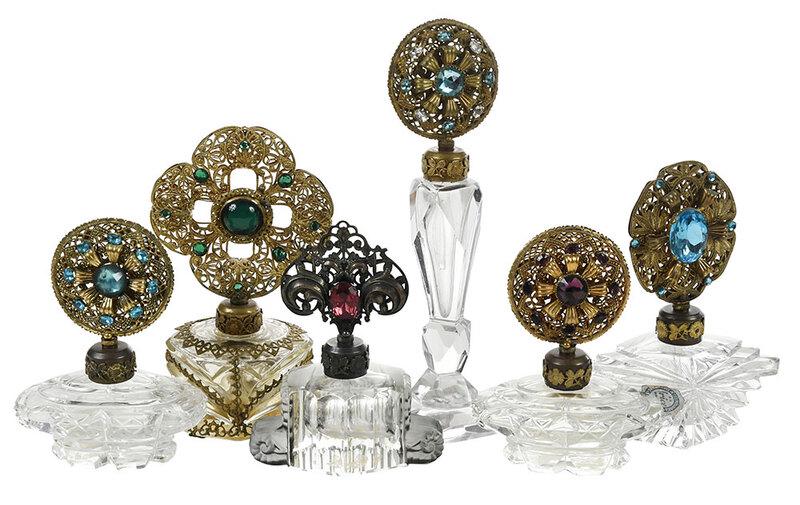 Six Perfumes with Gilt and Jeweled Stoppers: probably Czech, early 20th century, each with cut and molded glass bottles, gilt medallion jeweled stoppers, and applied gilt mounts to collars, four with partial "Irice" adhesive labels, 4-1/4 in. to